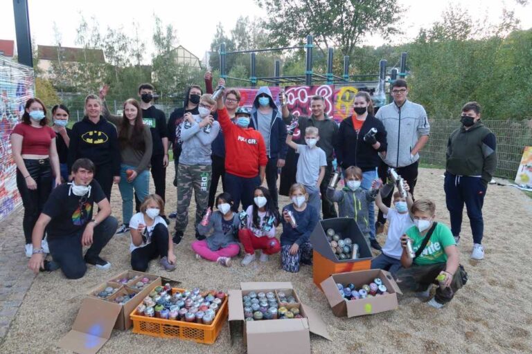 Eine Gruppe jugendlicher Sprayer schaut fröhlich in die Kamera.