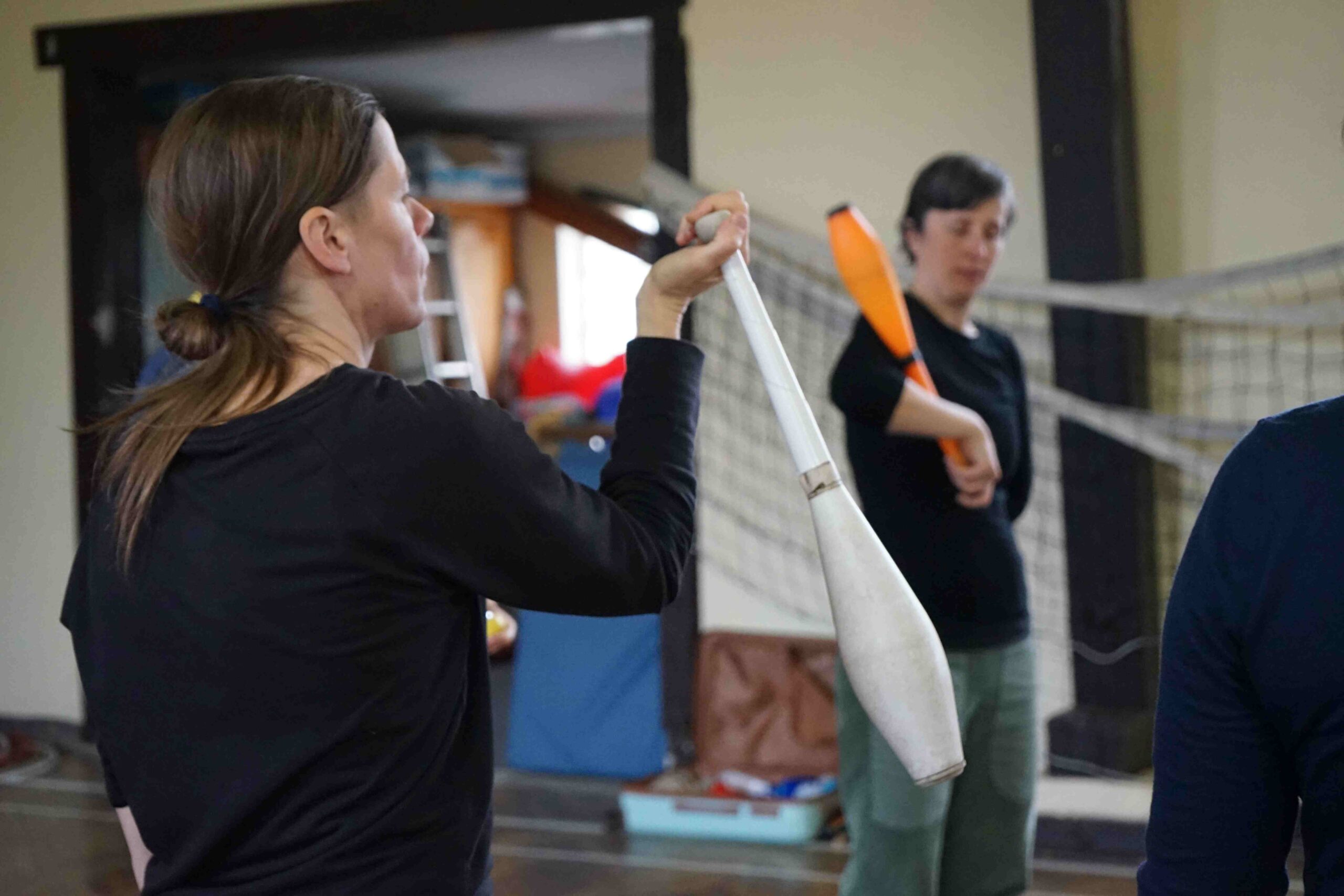 Im Vordergrund übt eine Person den Umgang mit einer Keule als Jonglageobjekt.