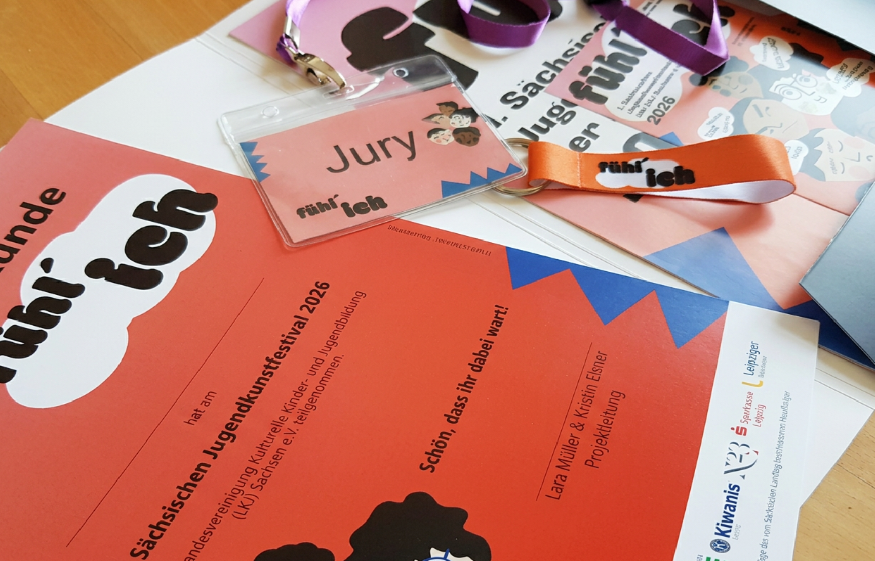 Eine Urkunde, ein Juryausweis und andere Materialien zum 1. Jugendkunstfestival liegen auf einem Tisch.