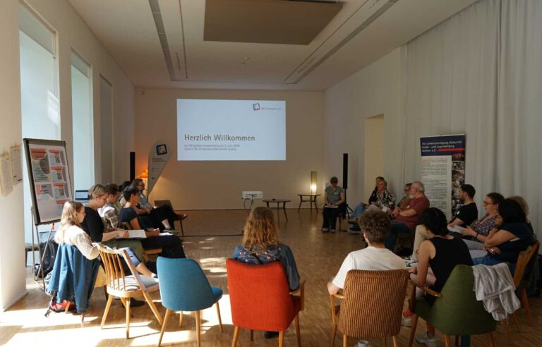 Die LKJ-Mitglieder sitzen im Kreis im Saal der GFZK Leipzig auf Retro-Stühlen der 50er Jahre.